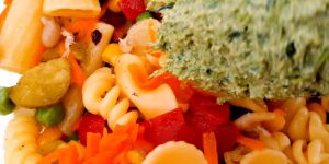 Stir the pasta salad thoroughly to ensure all the ingredients are well combined and coated with the green sauce.
